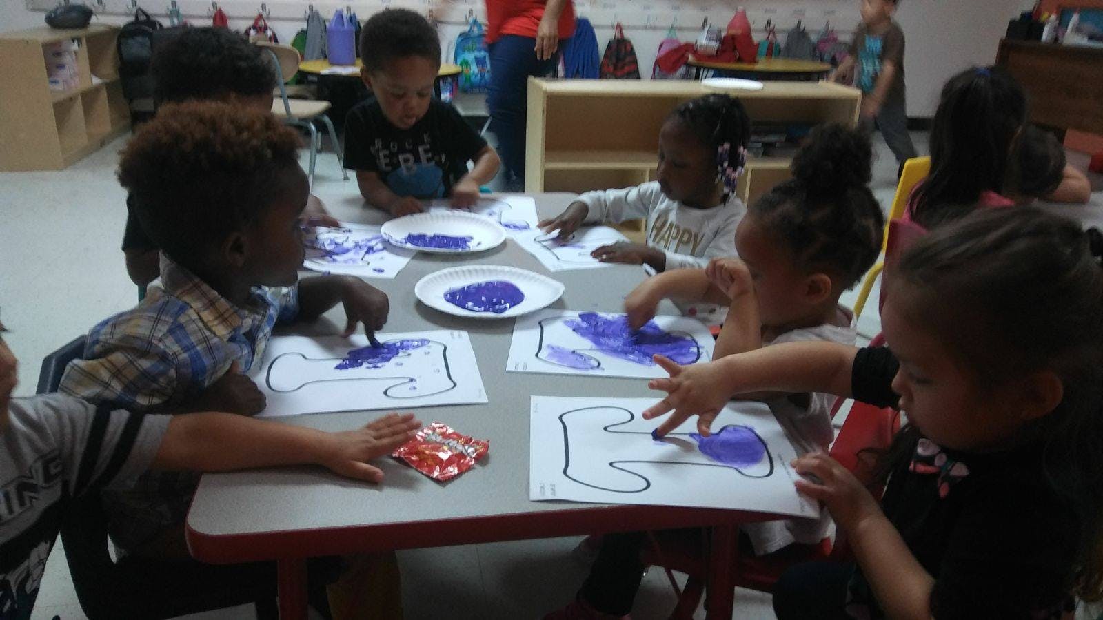 Children finger painting in a classroom