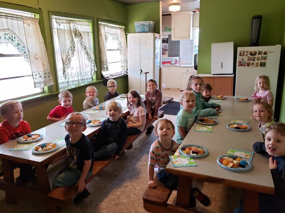 Children sitting at tables with plates of food