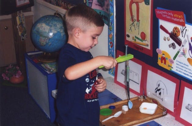 Child playing with a toy on a table in a classroom