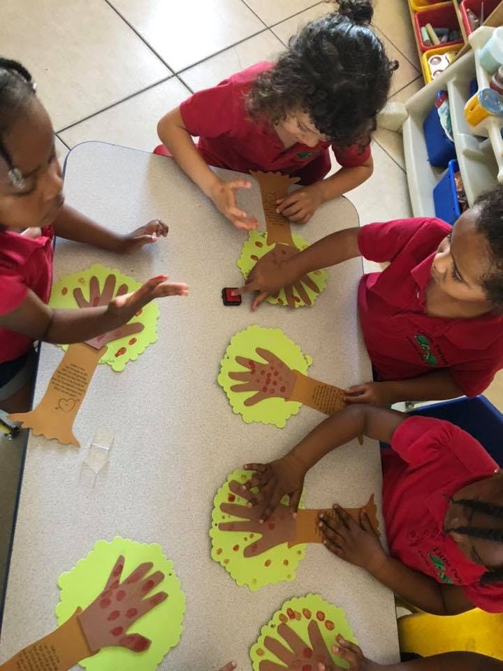 Children making tree crafts with handprints on a table