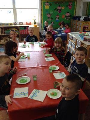 Children sitting at a long table in a classroom
