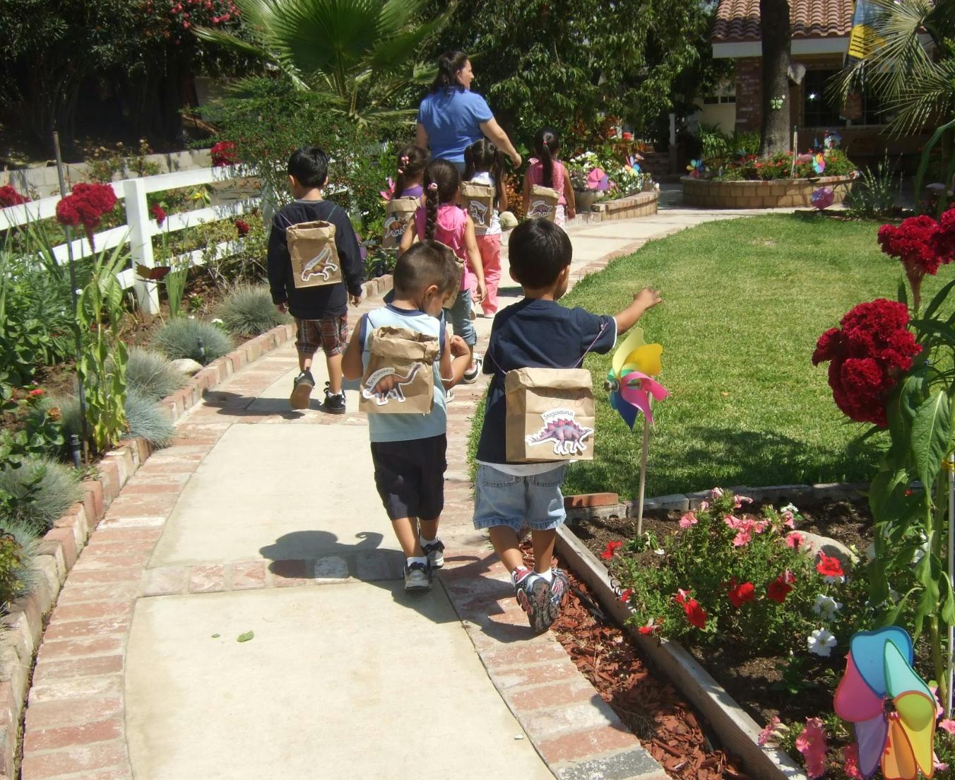 Children walking on a path with paper bags on their backs