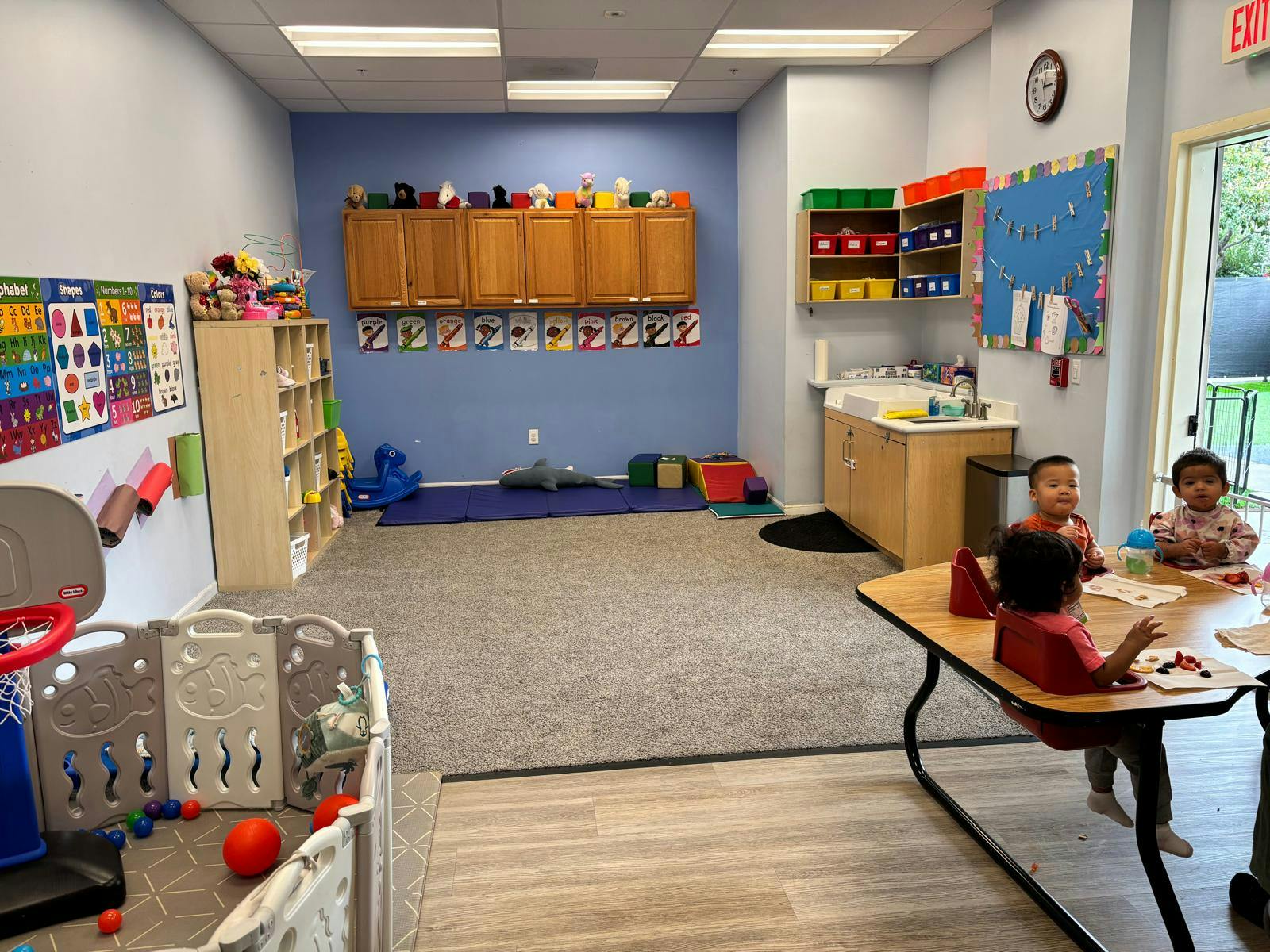 children sitting at a table in a classroom with play area