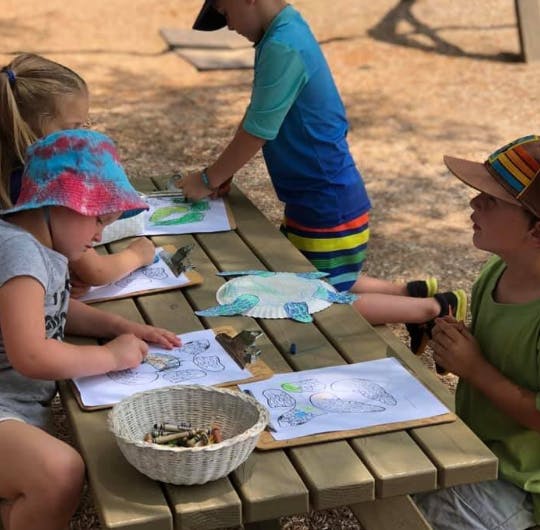 Children drawing at a picnic table outdoors