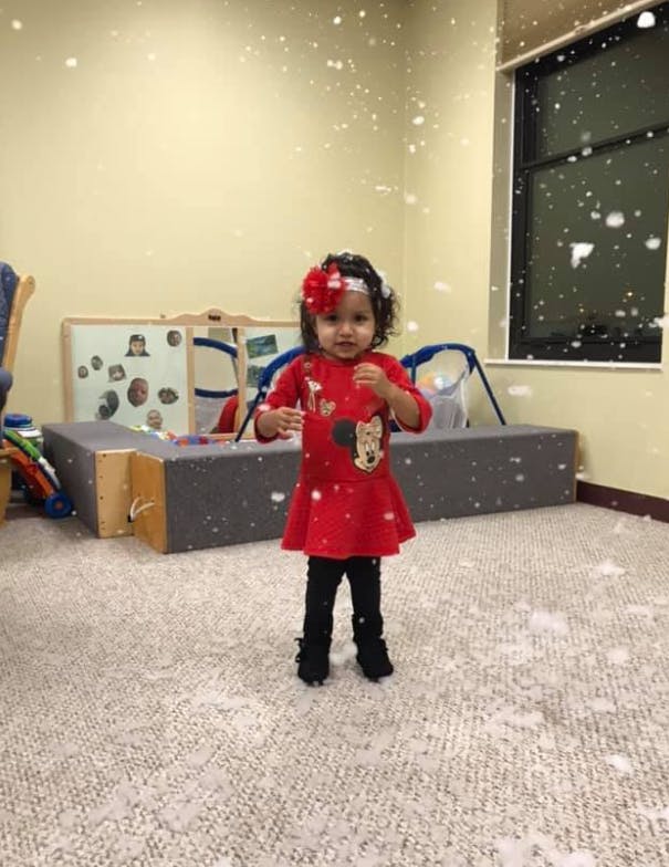 Child standing in a room with white specks falling