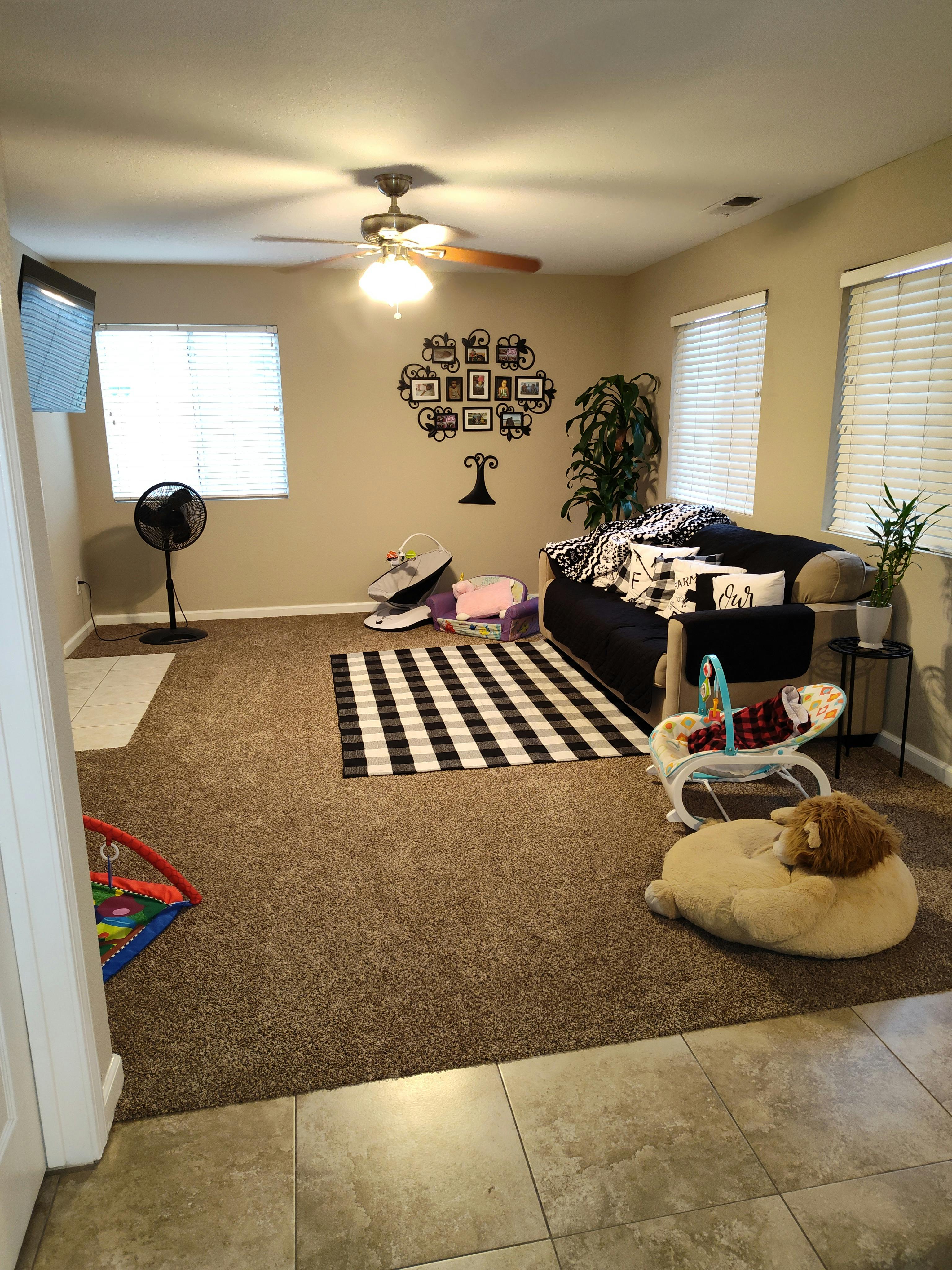 Living room with a couch, checkered rug, and baby items