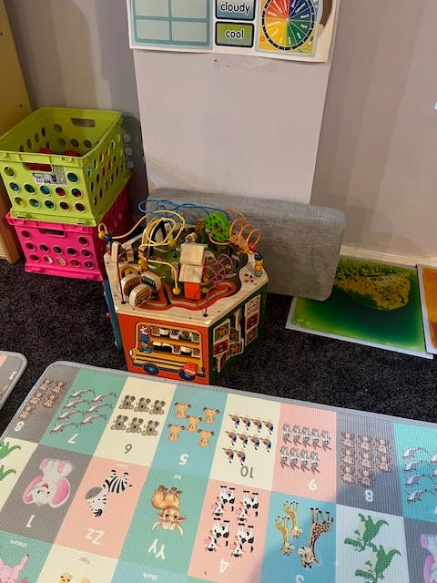 Children's play area with an activity cube, storage crates, and a number mat