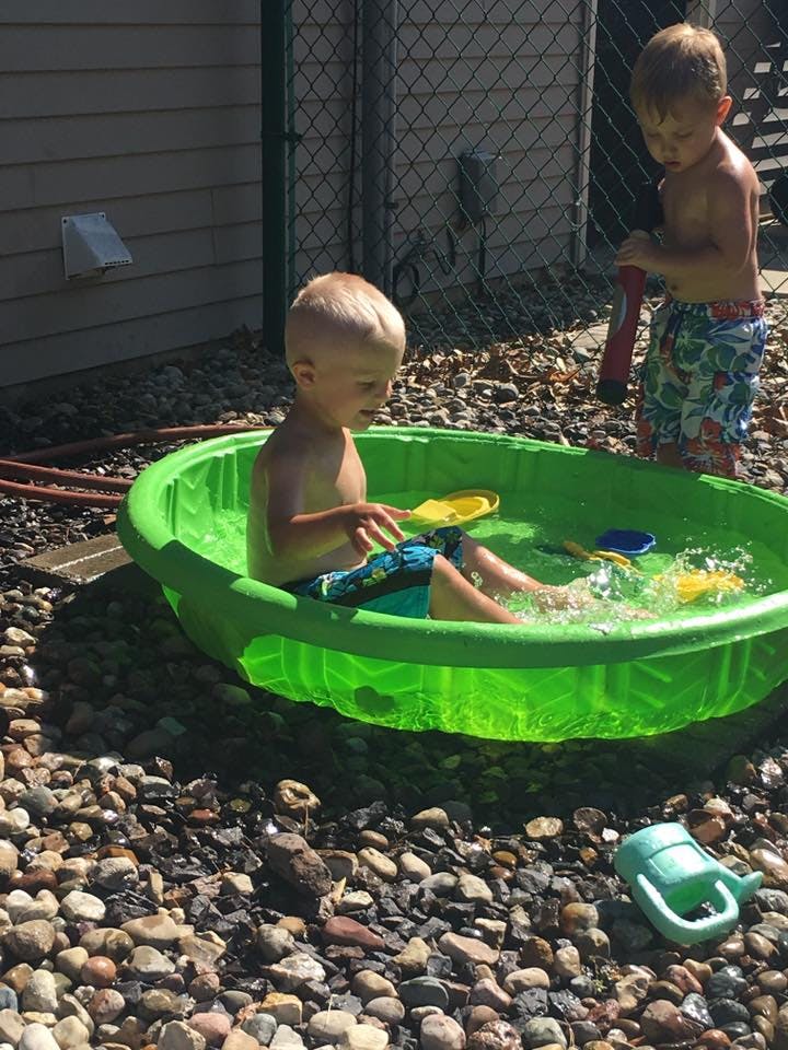Two children playing in a green wading pool