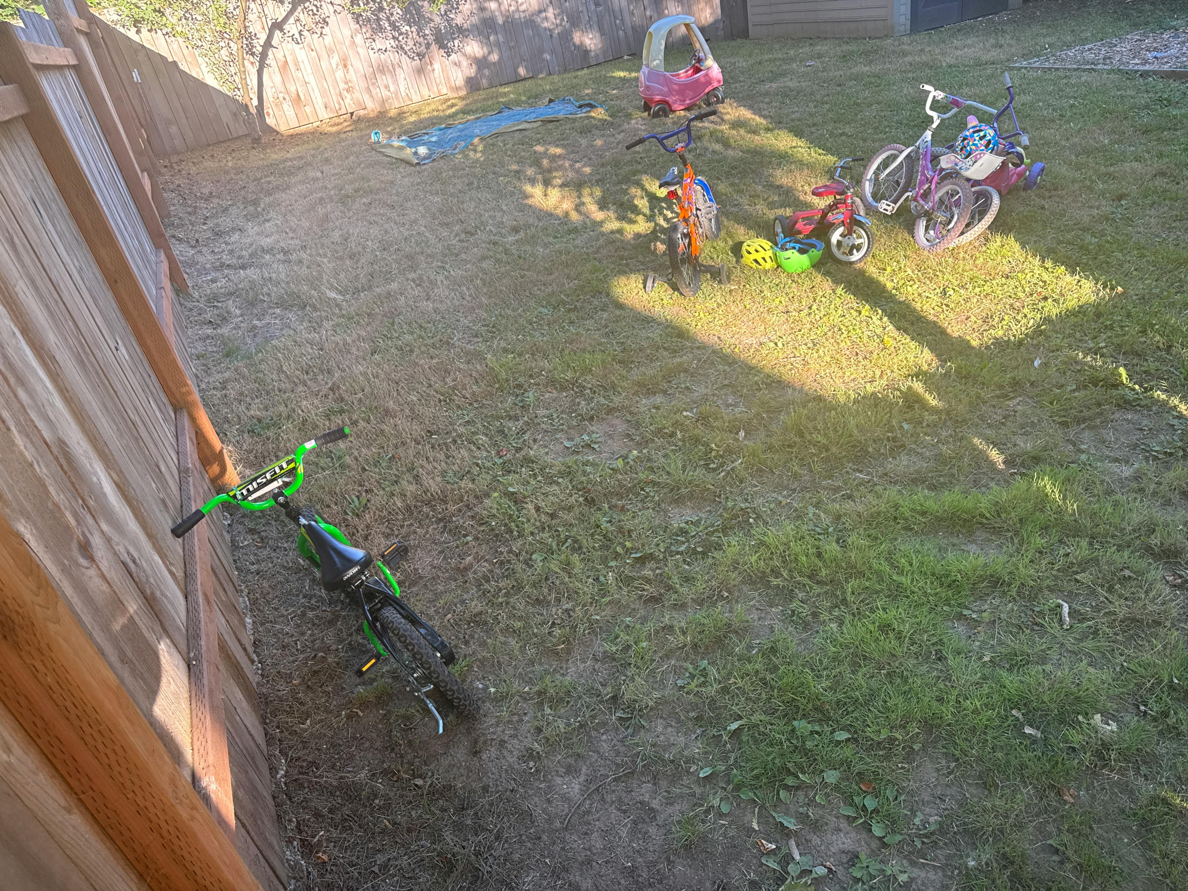 Children bicycles and ride-on toys scattered in a backyard