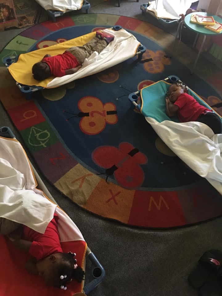 Children sleeping on cots in a classroom