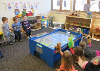 Children playing with a sand table in a classroom