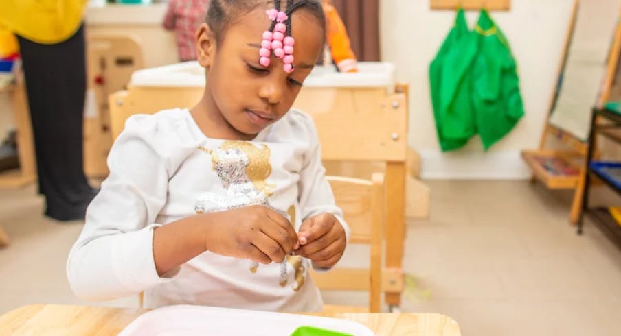 Child sitting at a table and manipulating a small object