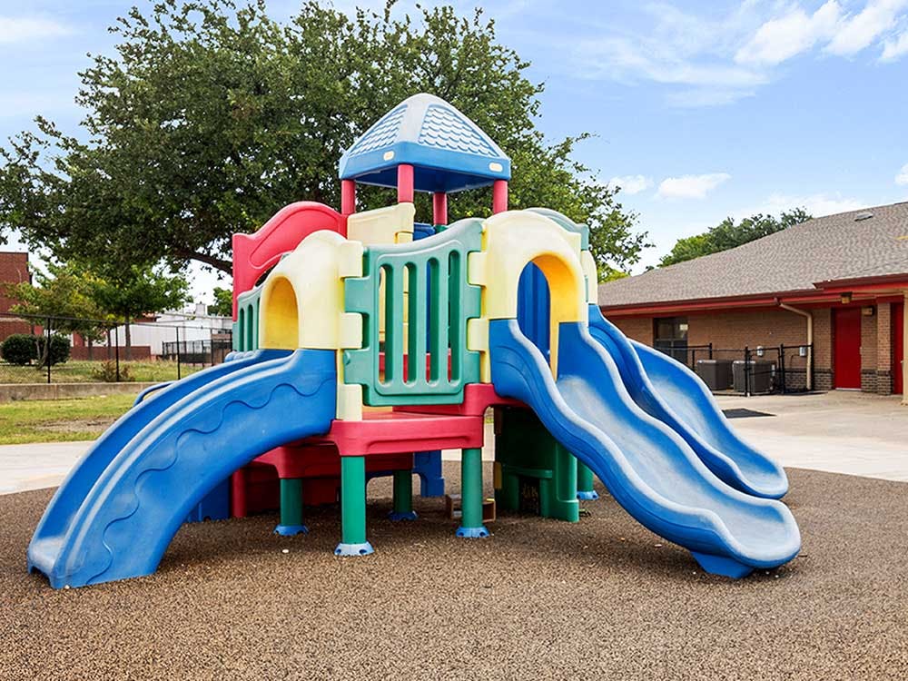 Colorful playground structure with multiple slides on a textured ground