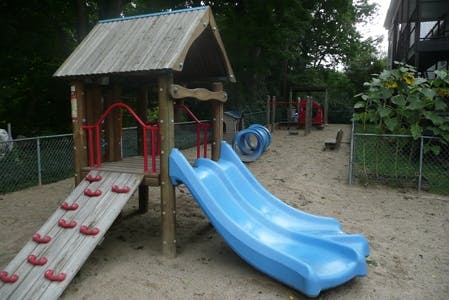 Playground with a wooden play structure, climbing ramp, and blue slide