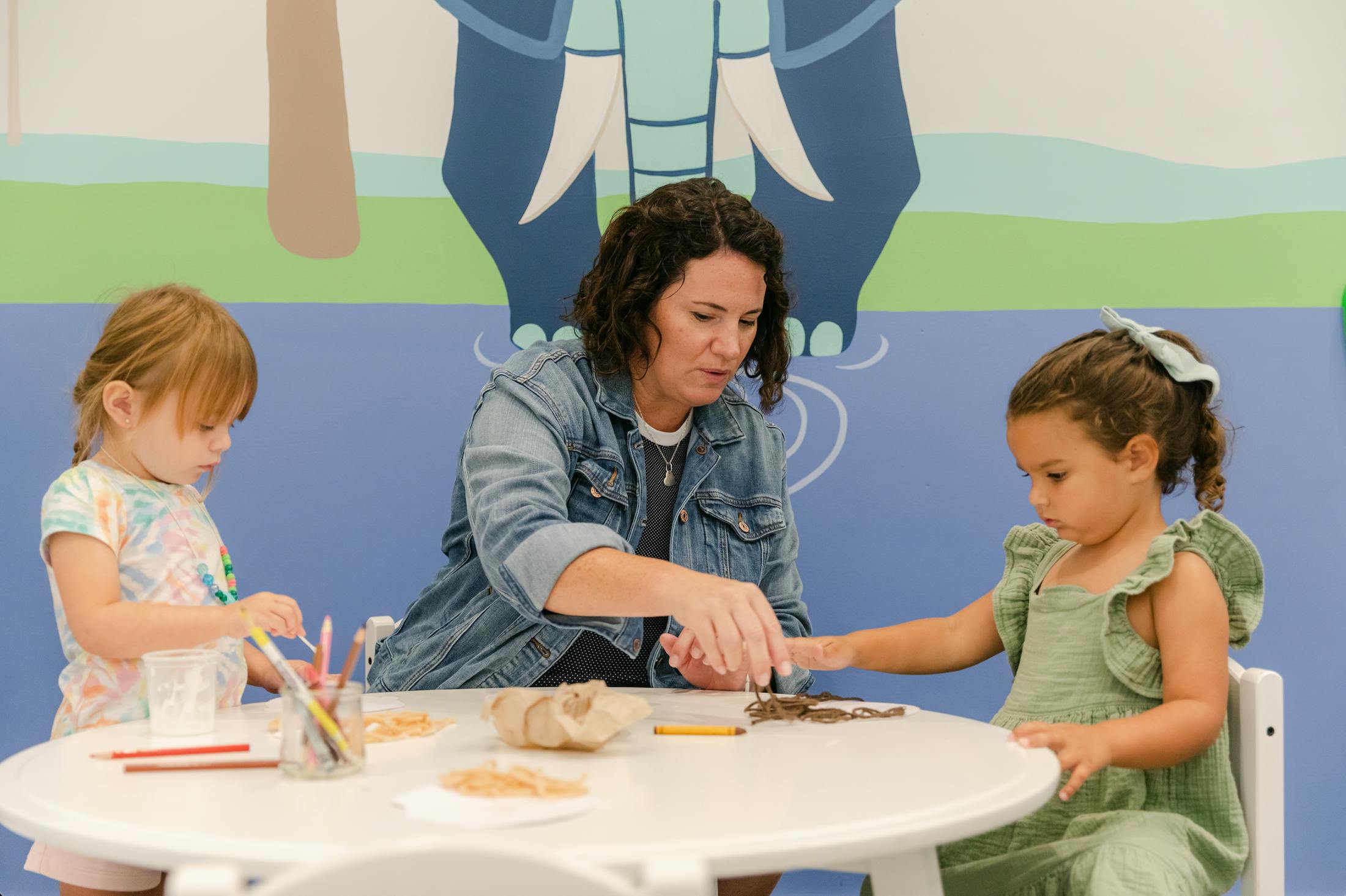 Person and two children at a table with art supplies
