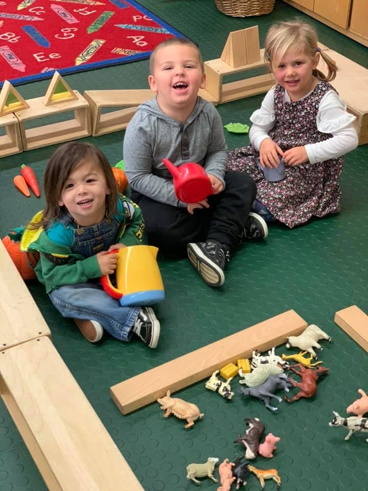 Three children playing on the floor with toys