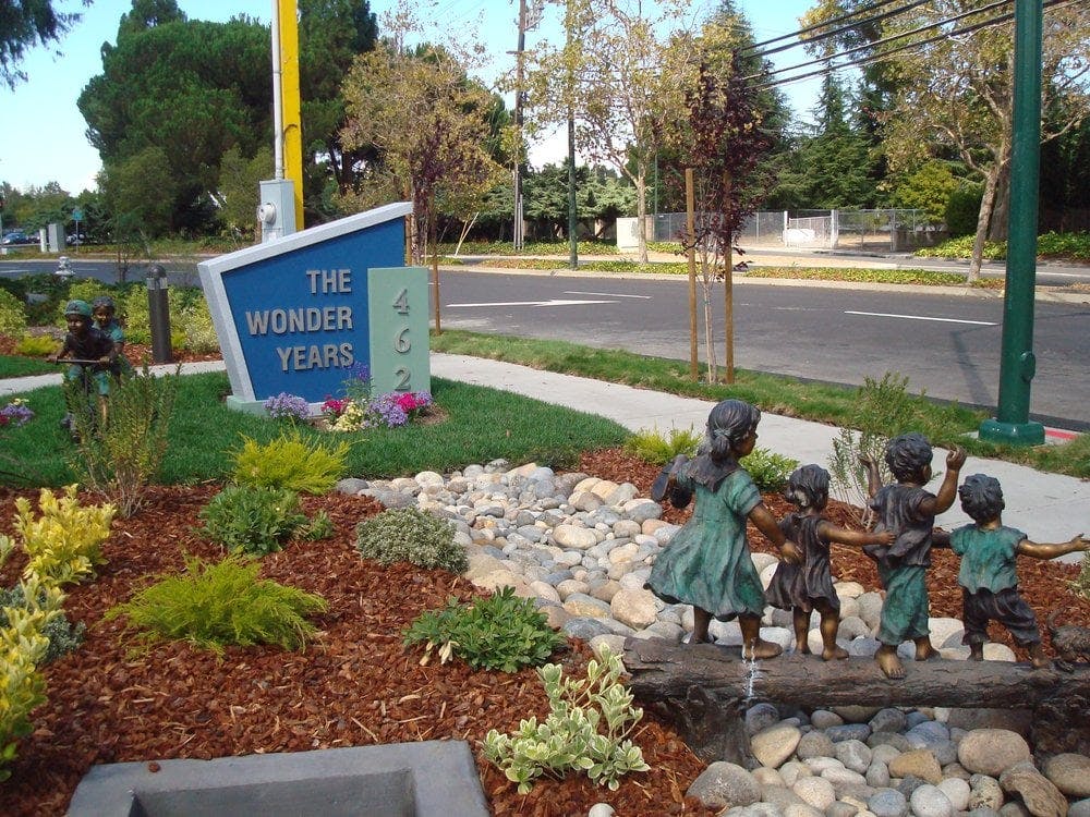 Sign for The Wonder Years with child statues in a garden