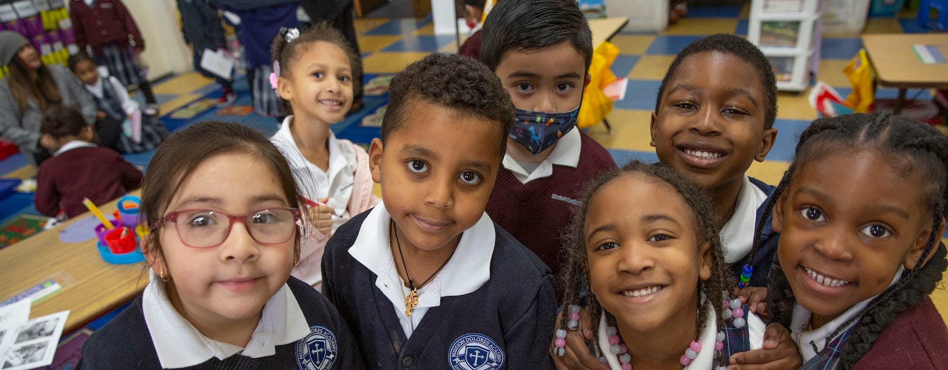 Group of children in a classroom smiling at the camera
