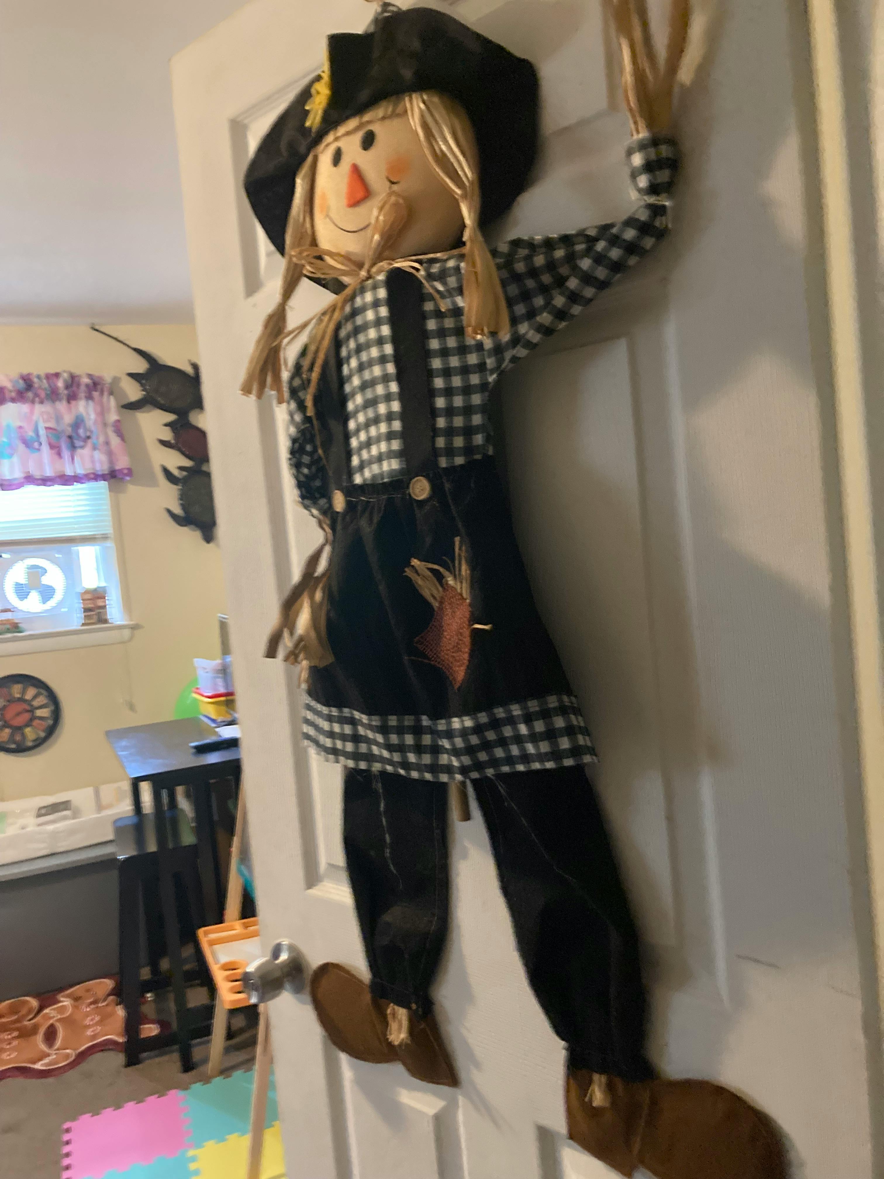 Scarecrow decoration in a black hat, black and white checkered shirt, and black pants