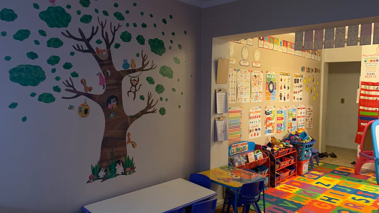 Playroom with tree mural on wall and colorful alphabet floor mats