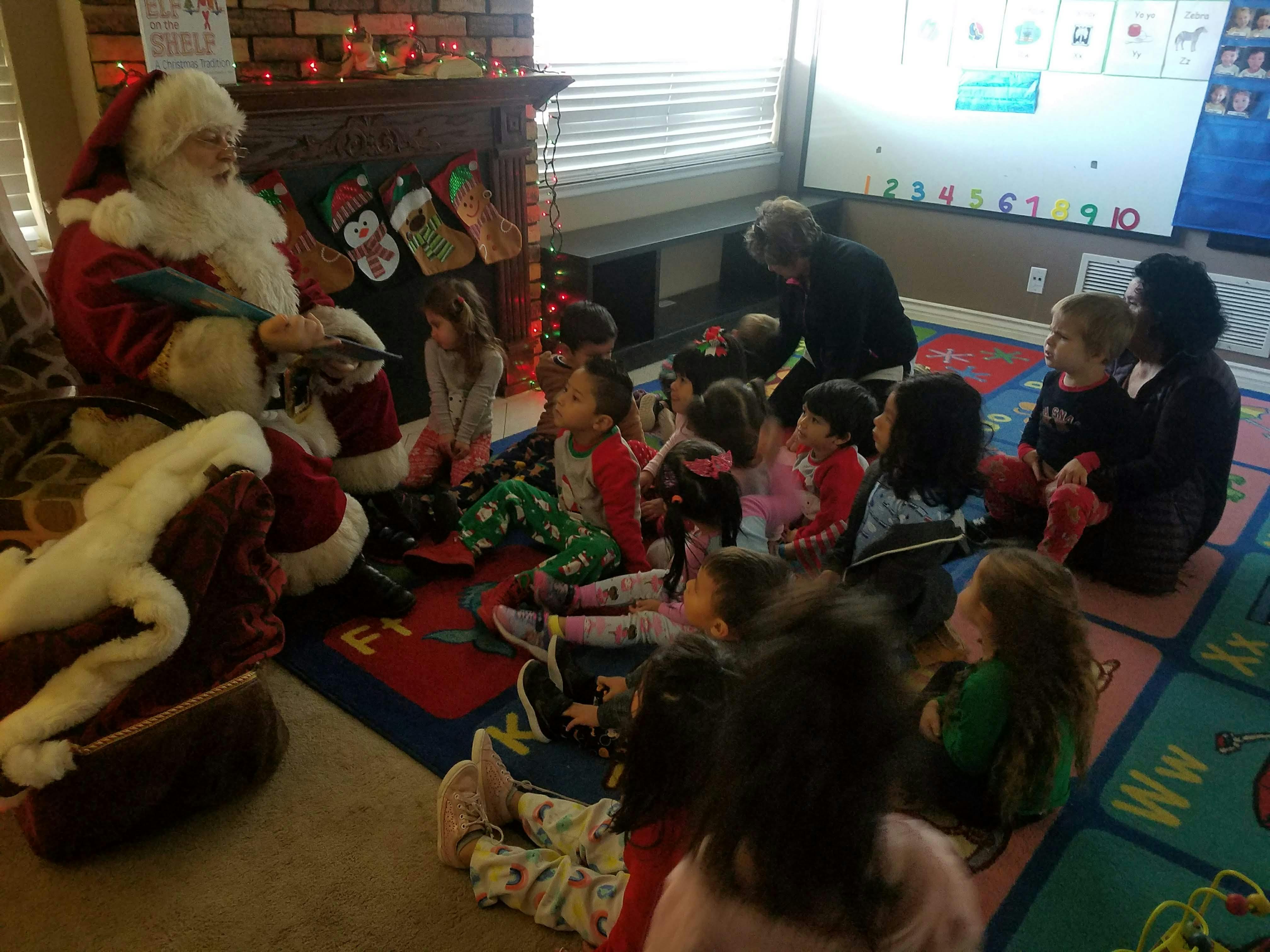 Person dressed as Santa Claus reading to a group of children