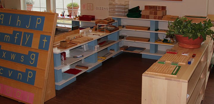 Montessori classroom with shelves of learning materials and alphabet board