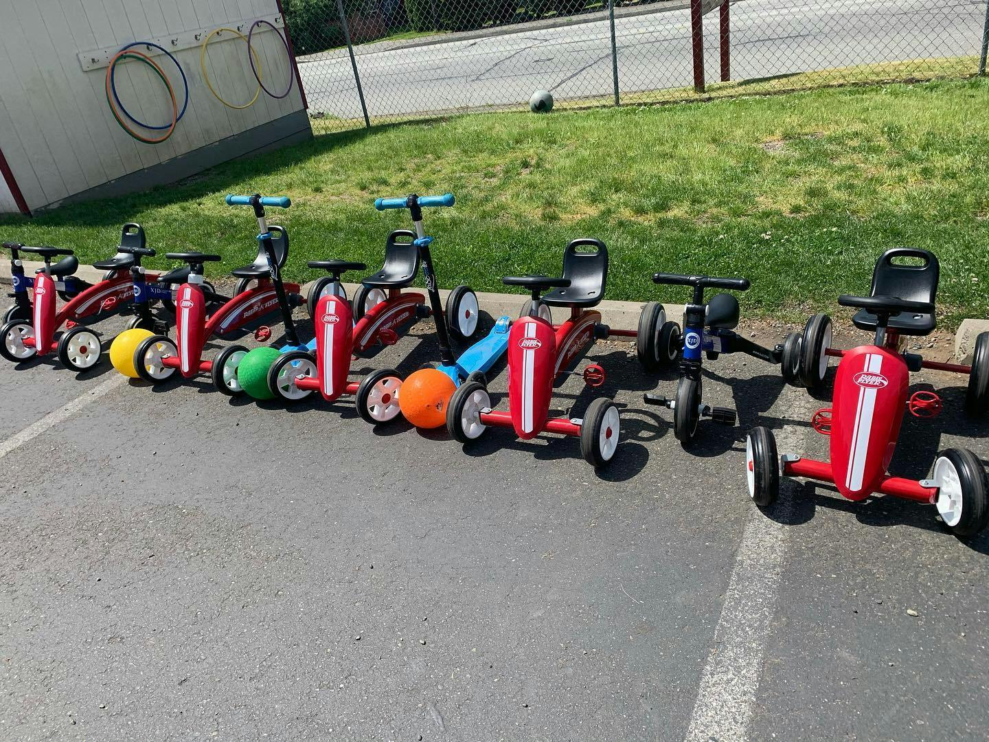 Row of children's pedal cars and scooters on pavement