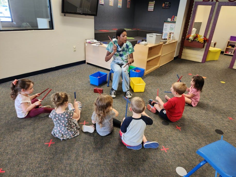 Person sitting on a chair with children sitting on the floor around them
