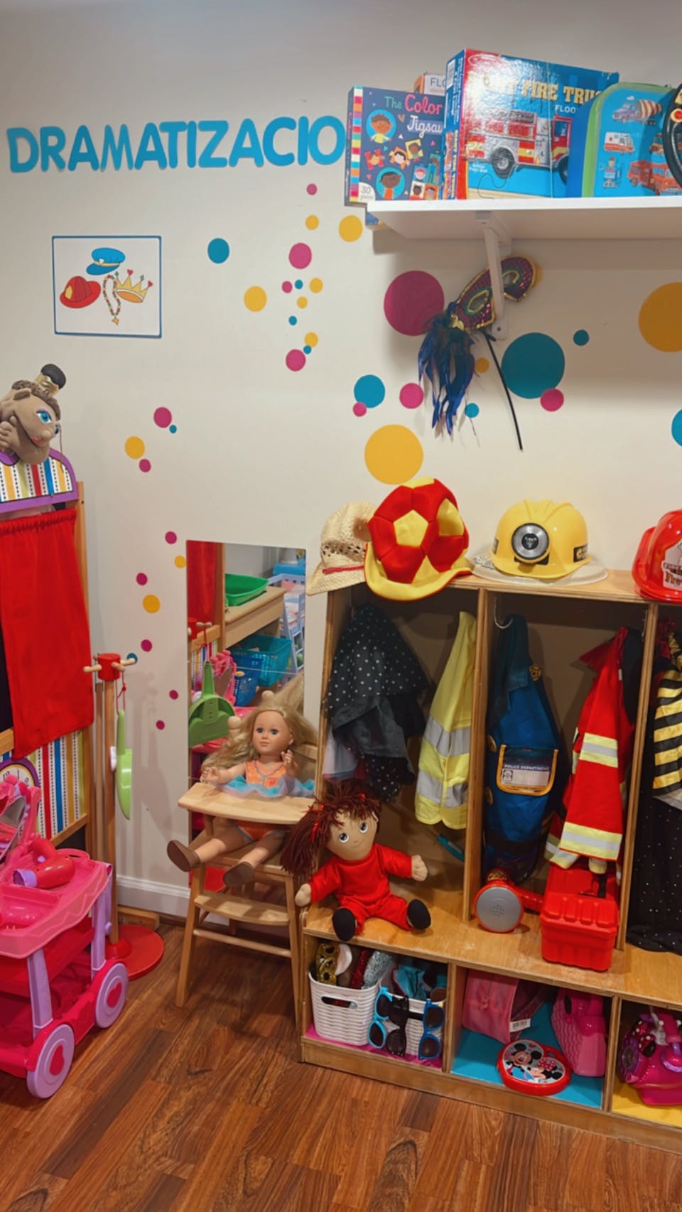 Playroom with dress-up clothes, dolls, and a sign that reads DRAMATIZACION