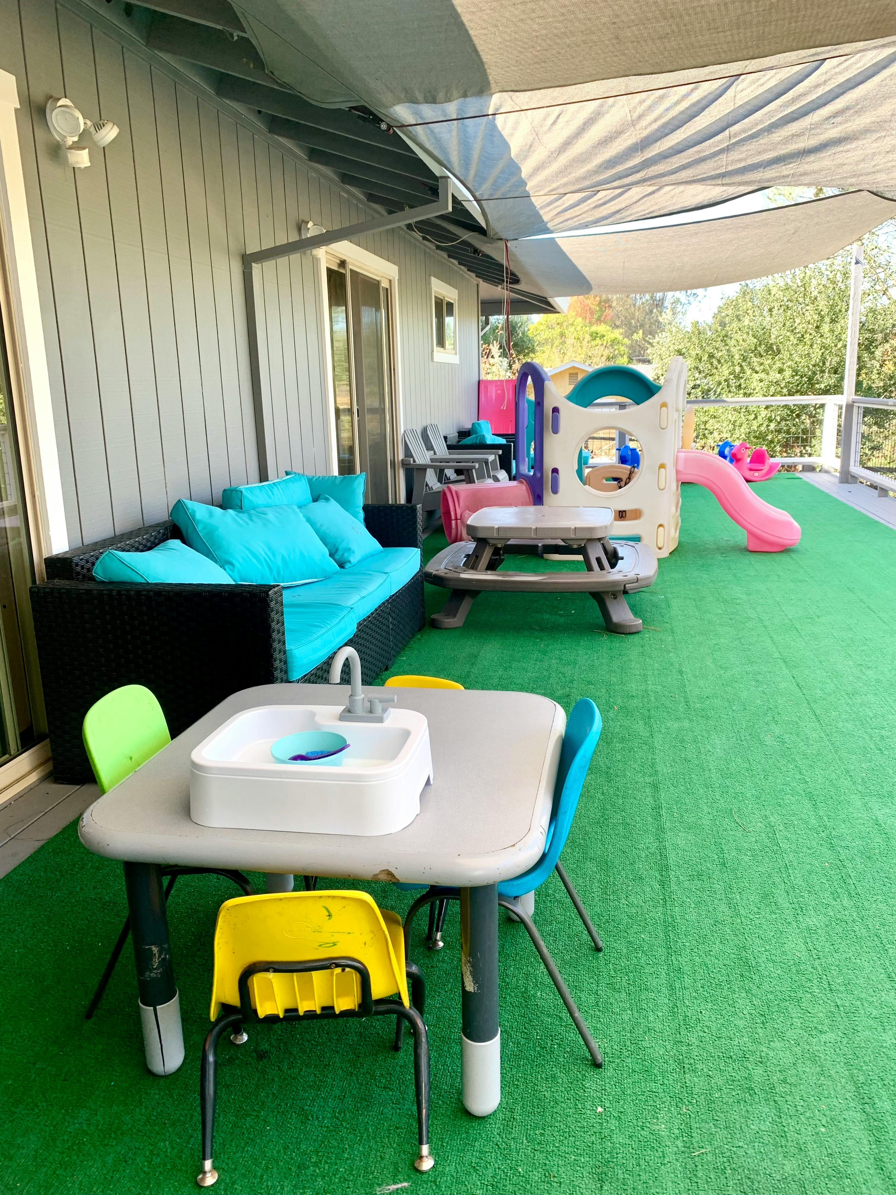 Outdoor patio with a blue sofa, children's play kitchen, and slide