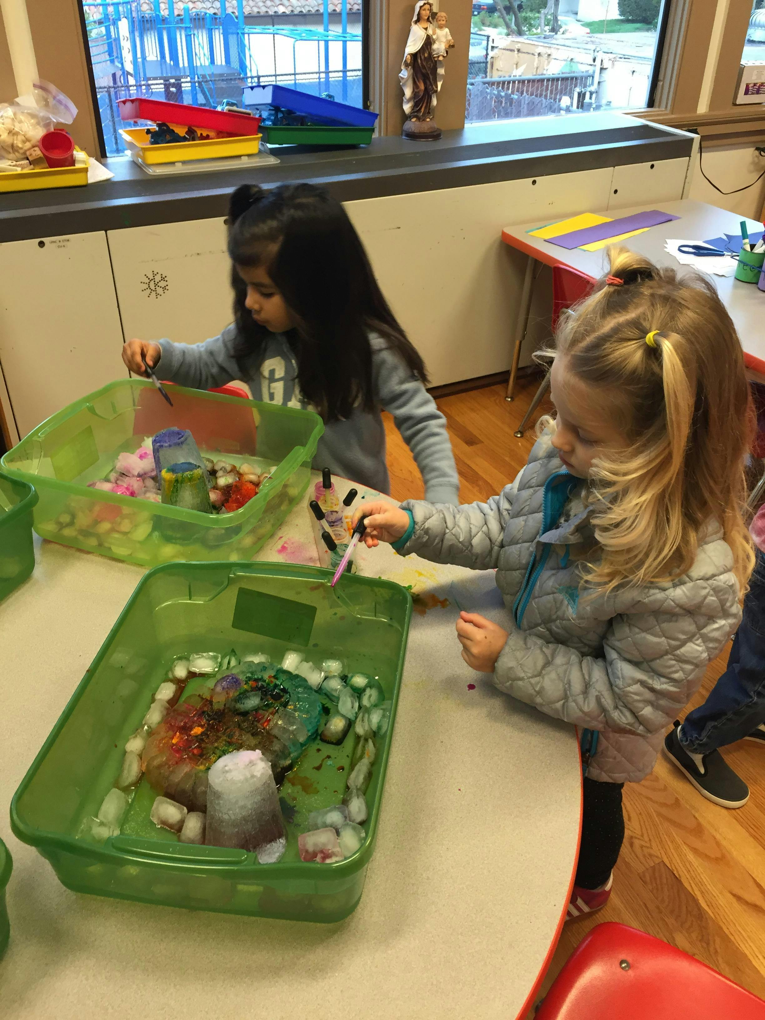 Two children playing with sensory bins in a classroom