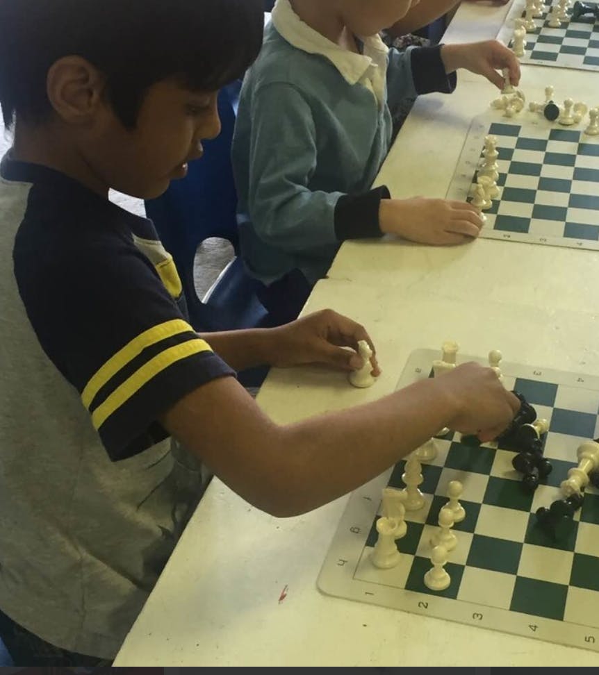 Two children playing chess at a table