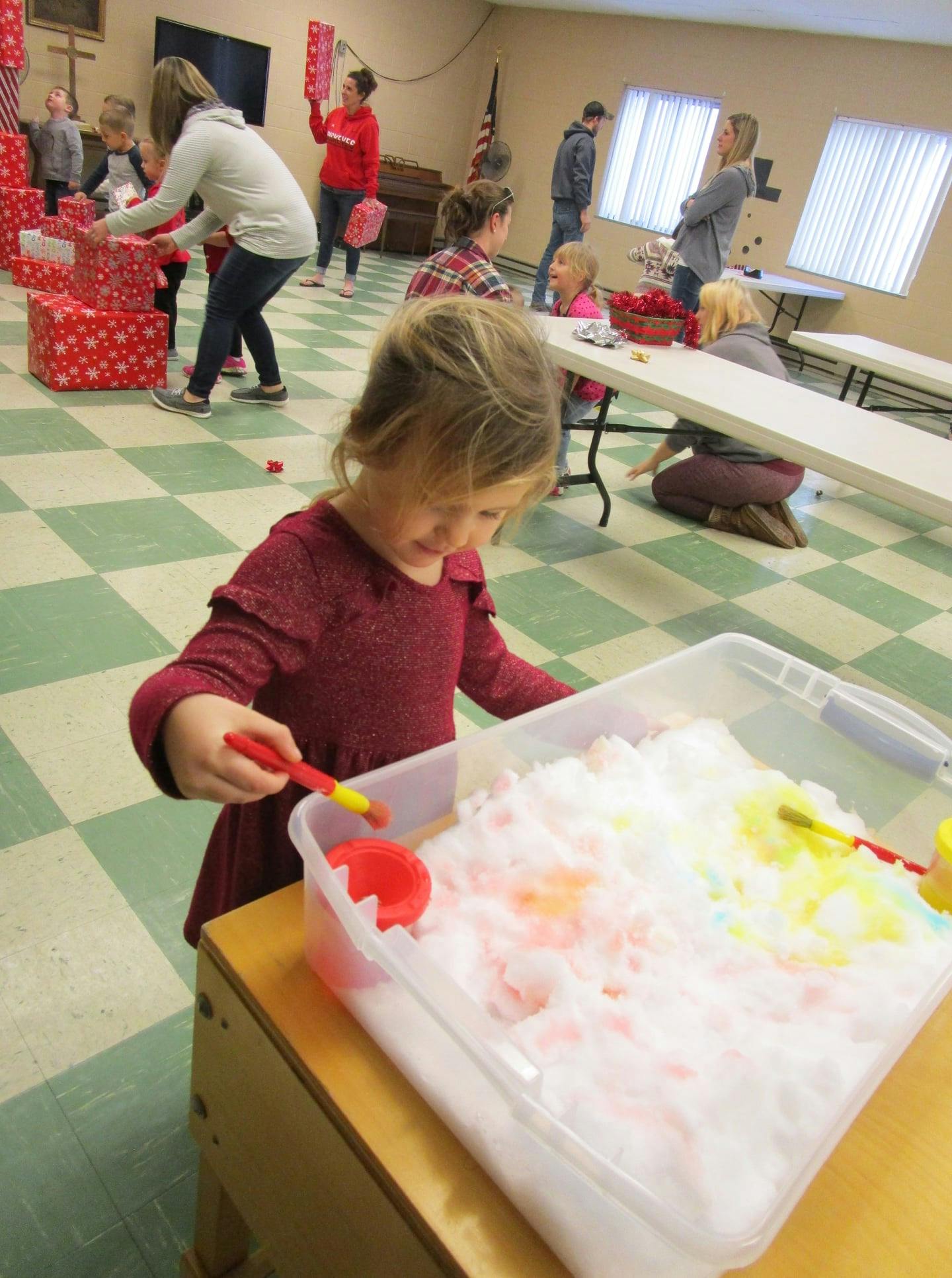 Child playing with colorful foam in a clear bin