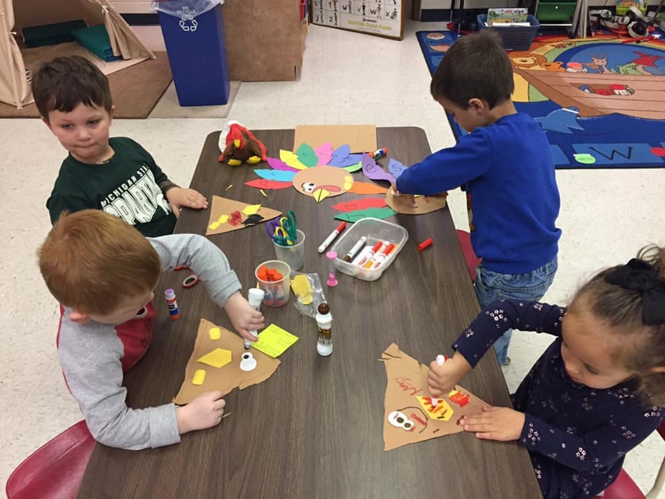 Children doing crafts at a table in a classroom