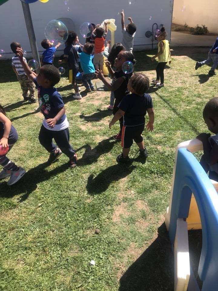 Children playing with bubbles outdoors on grass
