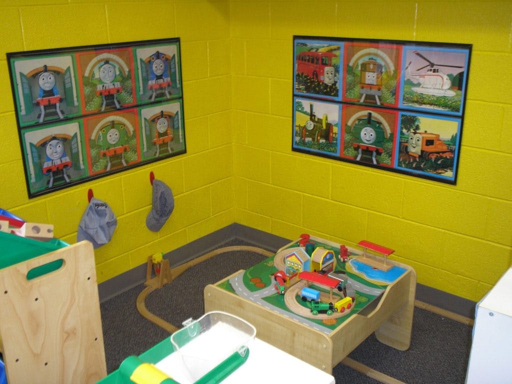 Playroom with train table and train-themed pictures on yellow walls