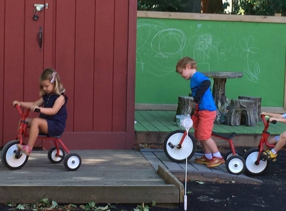 Two children riding tricycles outdoors