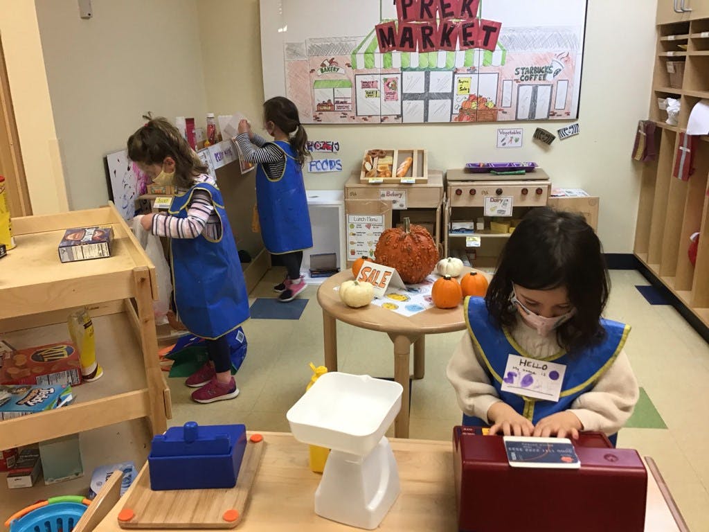 Children playing in a classroom with a "PREP MARKET" sign