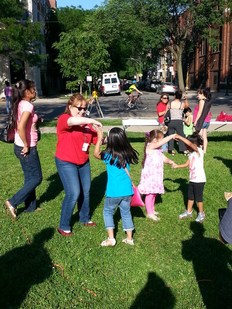 People and children dancing in a circle on grass