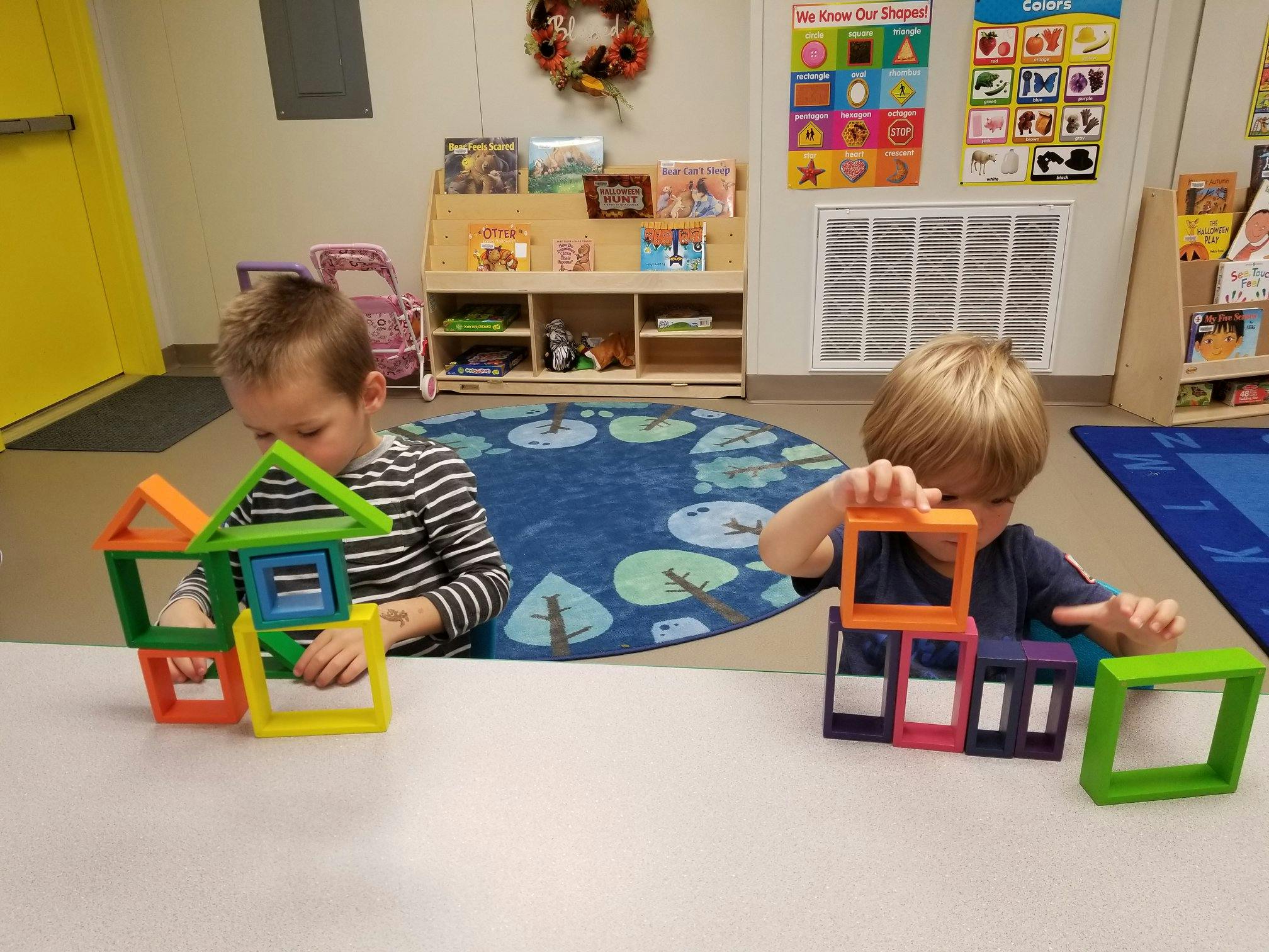 Two children playing with colorful magnetic building blocks at a table