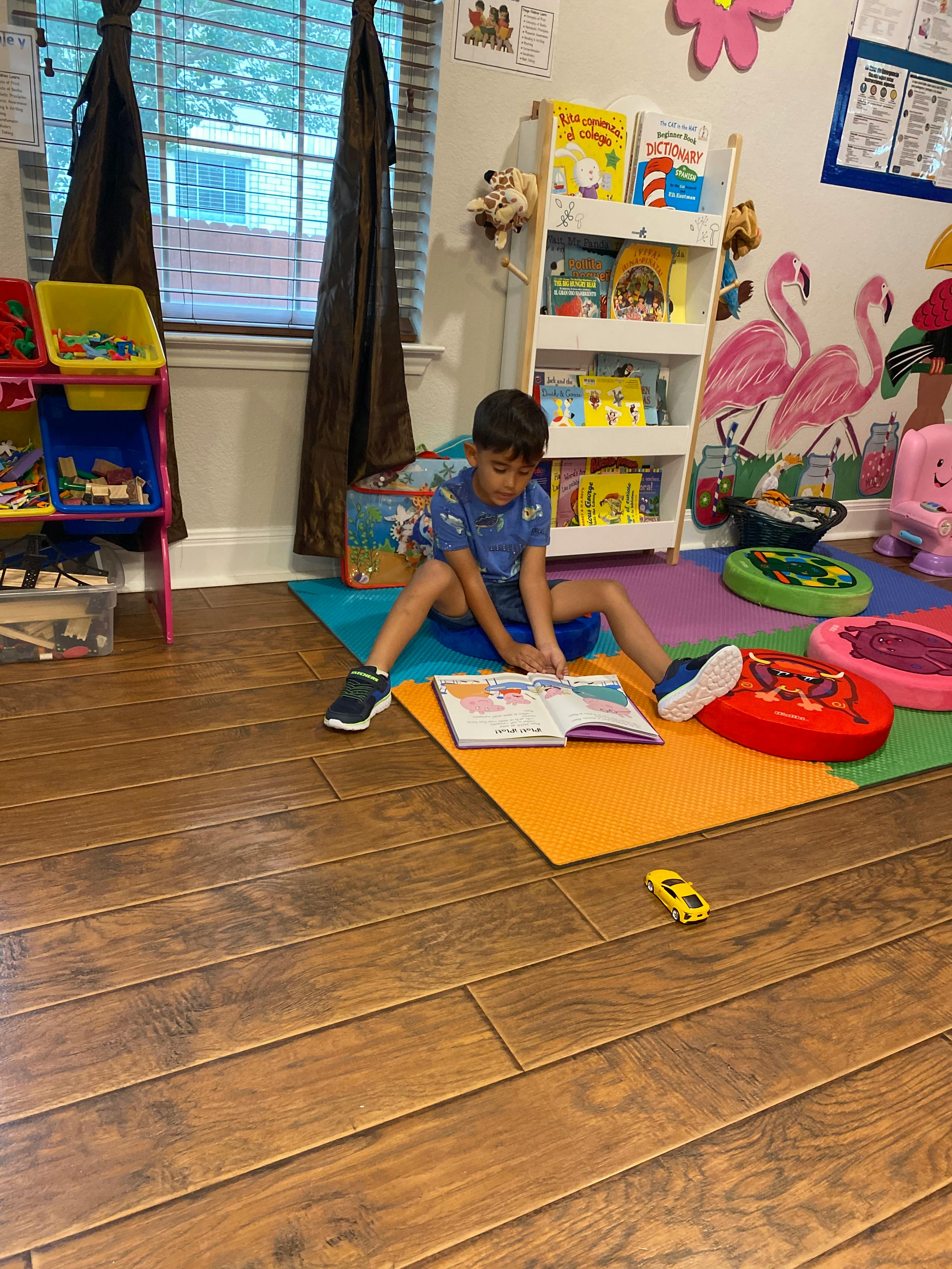 Child sitting on floor reading a book in a room with bookshelves