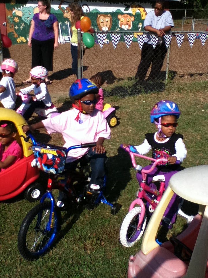 Children on bicycles and a ride-on toy outdoors