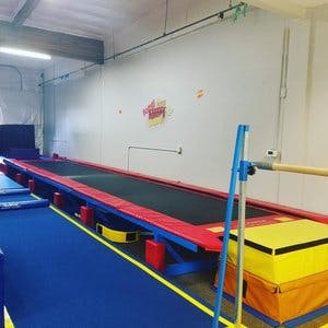 Gymnastics facility with long trampolines and blue mats