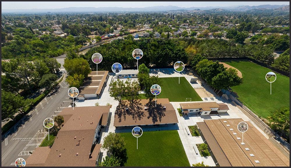 Aerial view of a school campus with buildings, sports fields, and trees