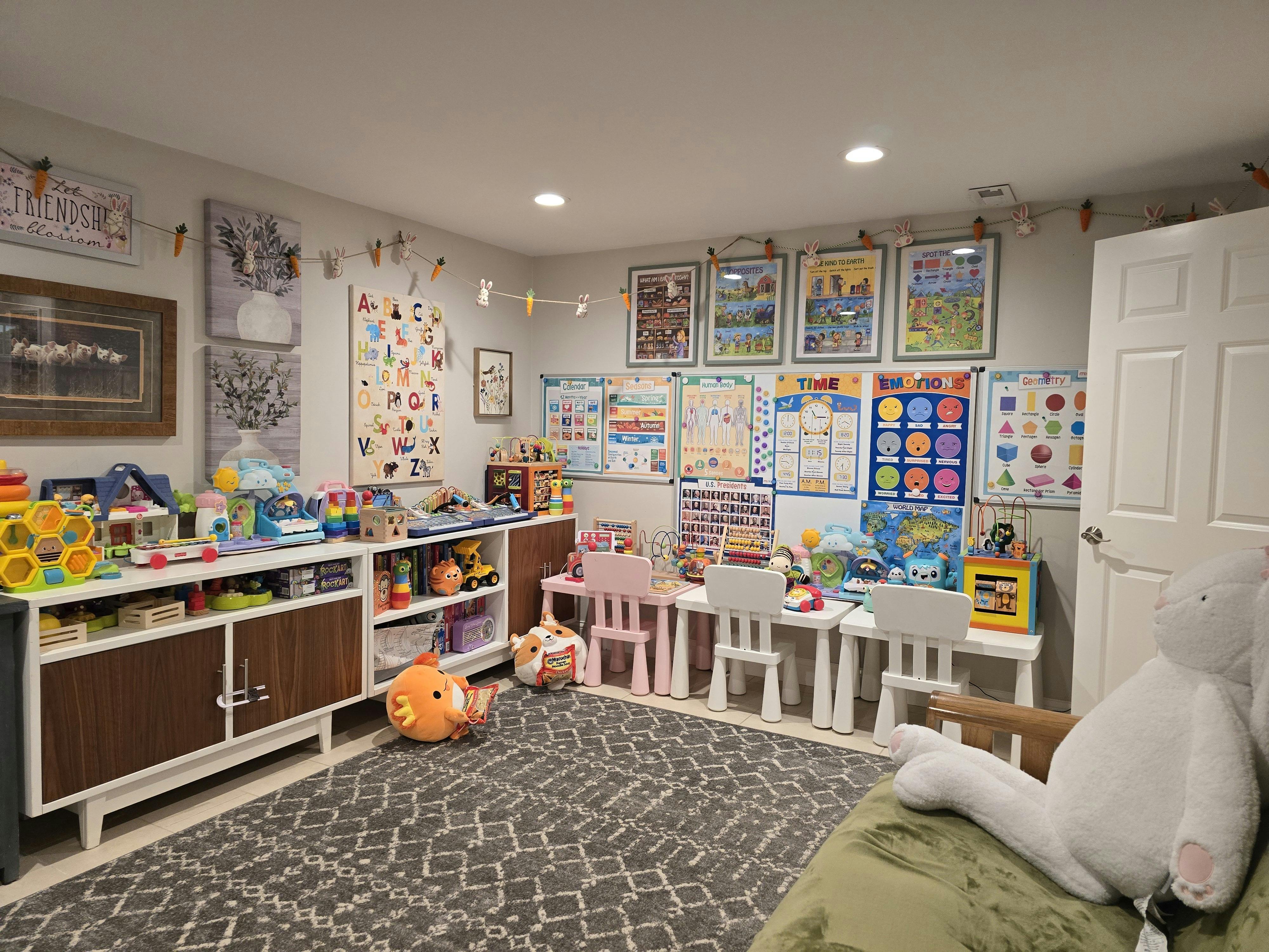 Playroom with shelves of toys, small tables and chairs, and educational posters on walls