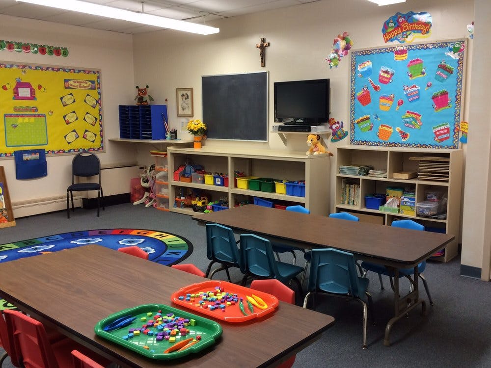 Classroom with tables, chairs, and shelves with toys and learning materials