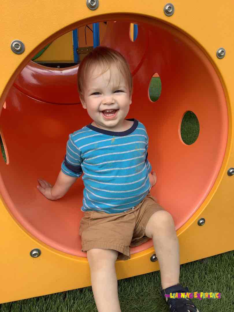 Child sitting in a yellow and orange play tunnel