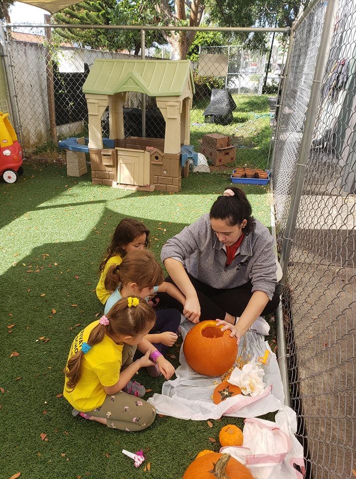Person carving a pumpkin with children watching