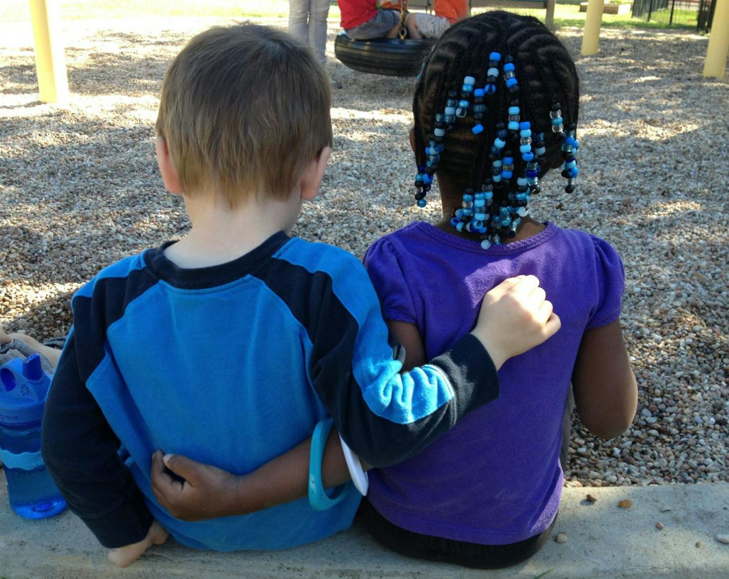 Two children sitting with arms around each other