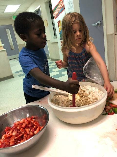 Two children mixing ingredients in a large bowl